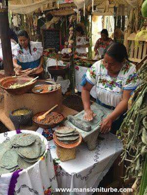 two women are preparing food at an outdoor market table with baskets and plates on it