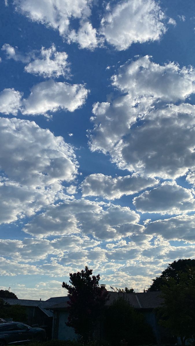 the sky is filled with white clouds and blue skies are in the foreground, some houses on the far side