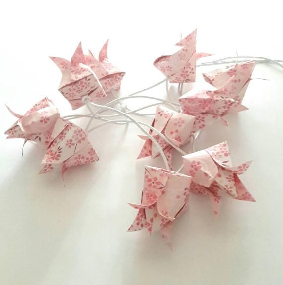 several pink origami birds on white background with string and wires in the foreground