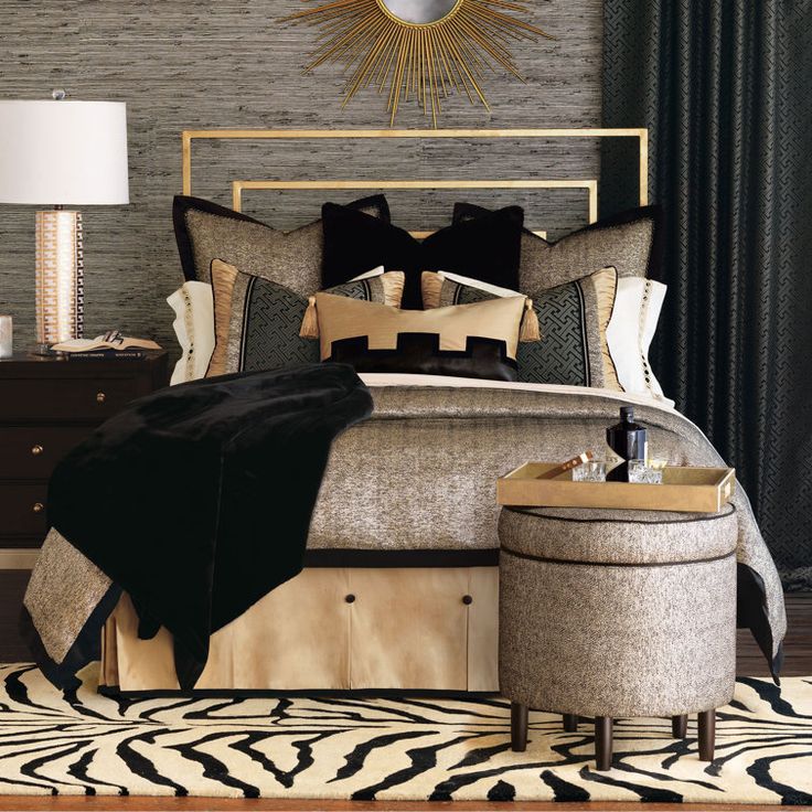 a bedroom with a large bed covered in black and gold pillows