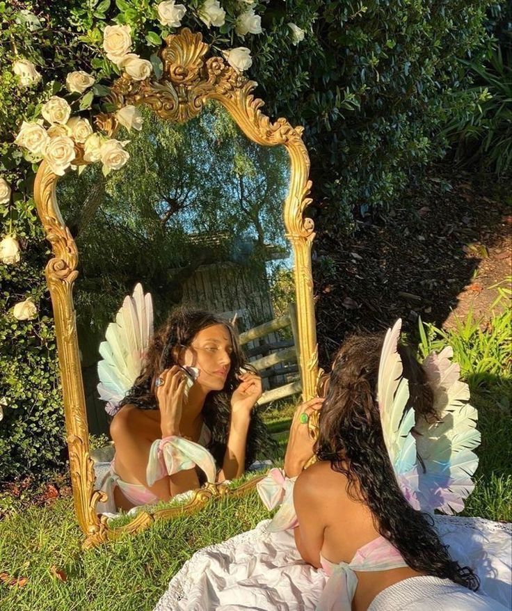 two women sitting on the grass in front of a mirror