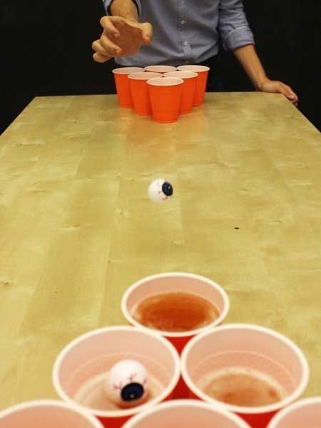 a man sitting at a table with cups on it and one person reaching for something