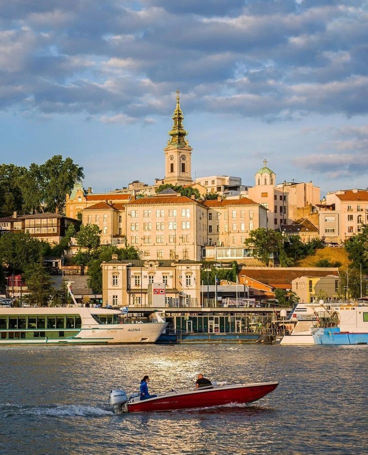 a man in a red boat on the water near some buildings and a clock tower