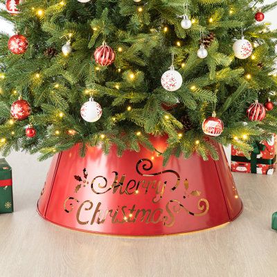 a christmas tree in a red bucket with ornaments around it and the words merry christmas