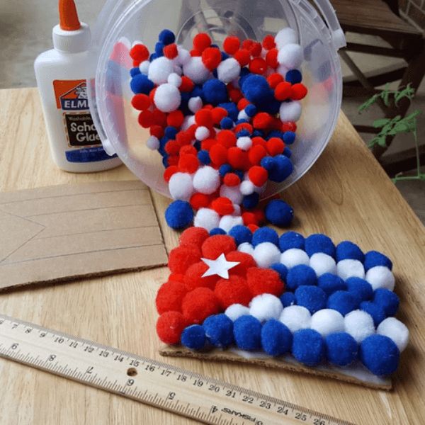 some red, white and blue pom poms are on a table next to a ruler