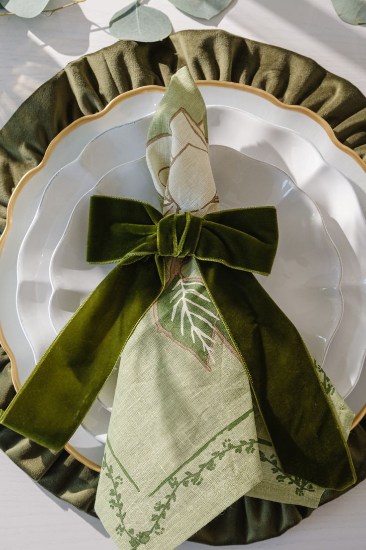 the napkins are folded on top of each other and tied with green ribbon around them