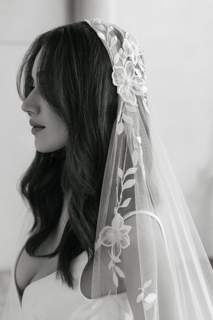 black and white photograph of a woman wearing a wedding veil with flowers on the side