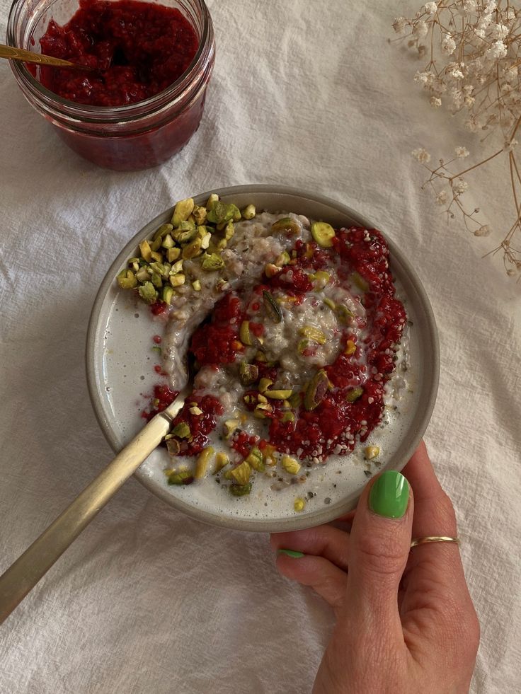 a person is holding a spoon in a bowl with yogurt and granola