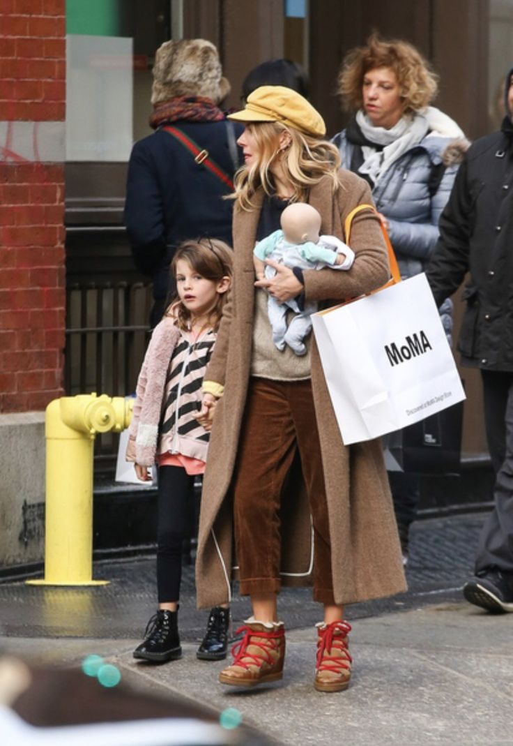 a woman holding a baby while walking down the street