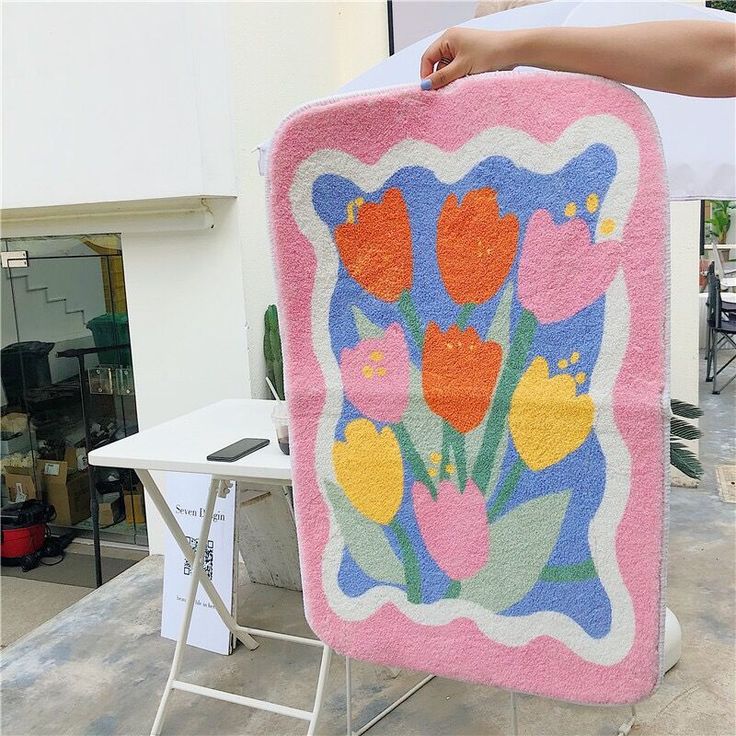 a woman is holding up a pink blanket with flowers on it