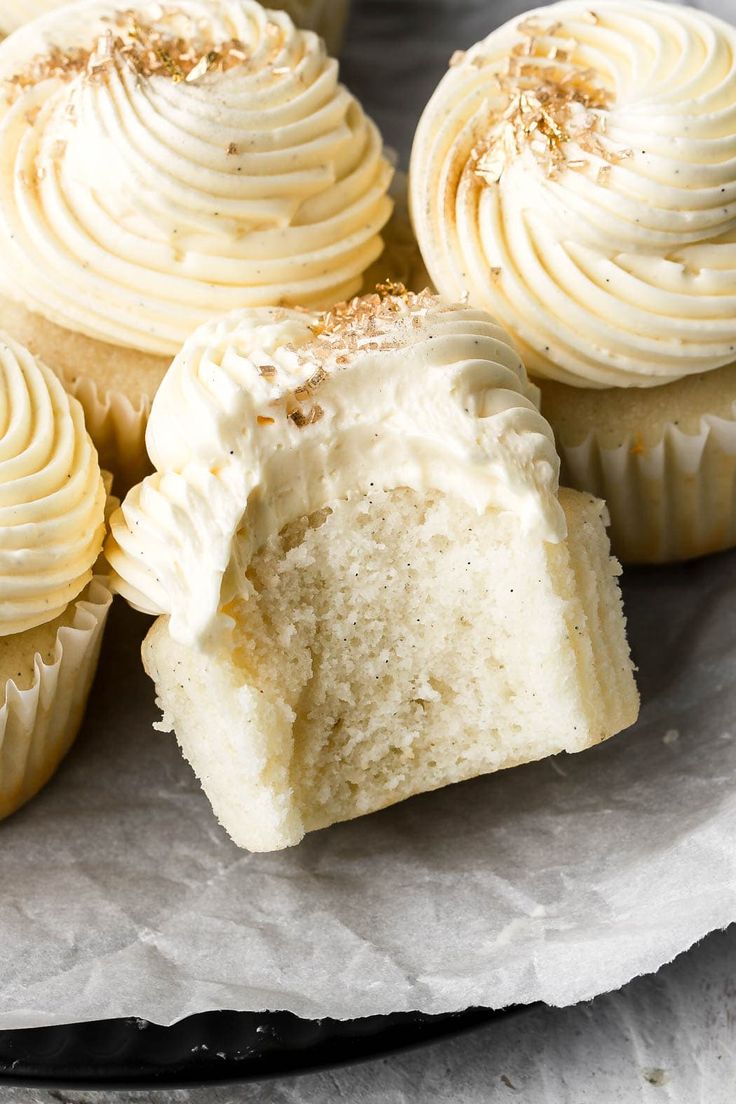 several cupcakes with white frosting and sprinkles on top sitting on a plate