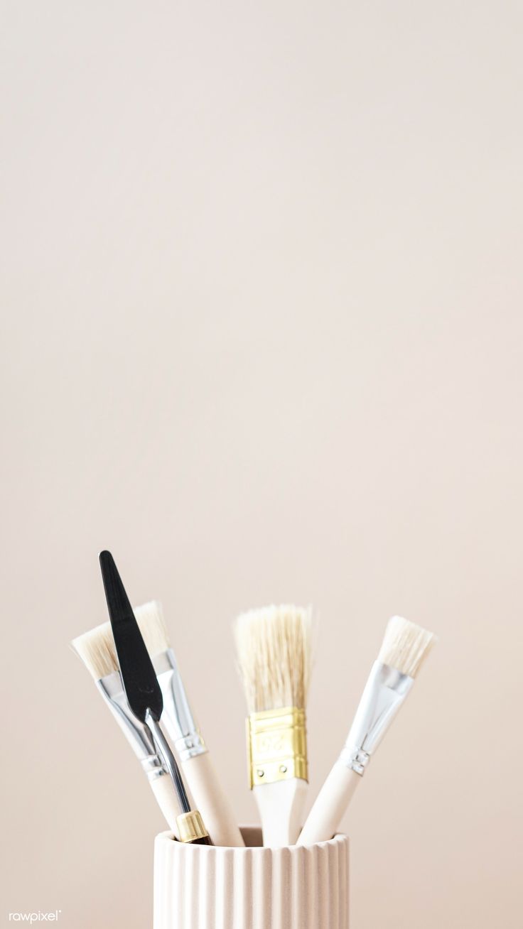 four brushes in a white cup on a table