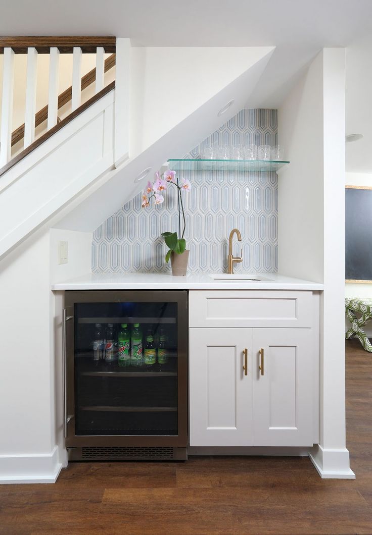 a white kitchen with an under counter beverage dispenser next to the stairs