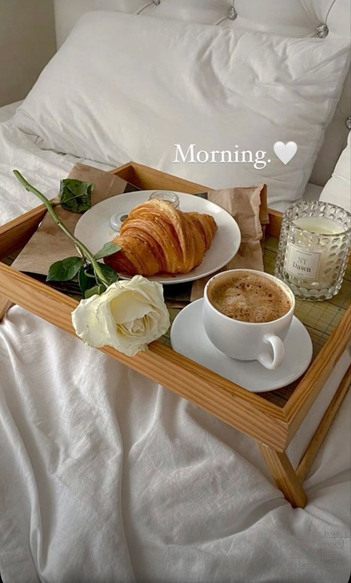 breakfast tray with coffee and croissant on bed