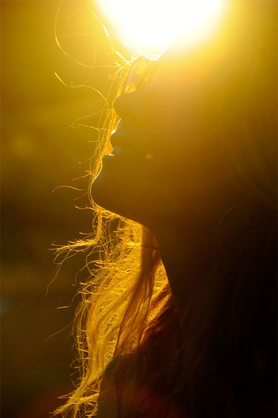 a woman's face with the sun shining behind her and texting in spanish