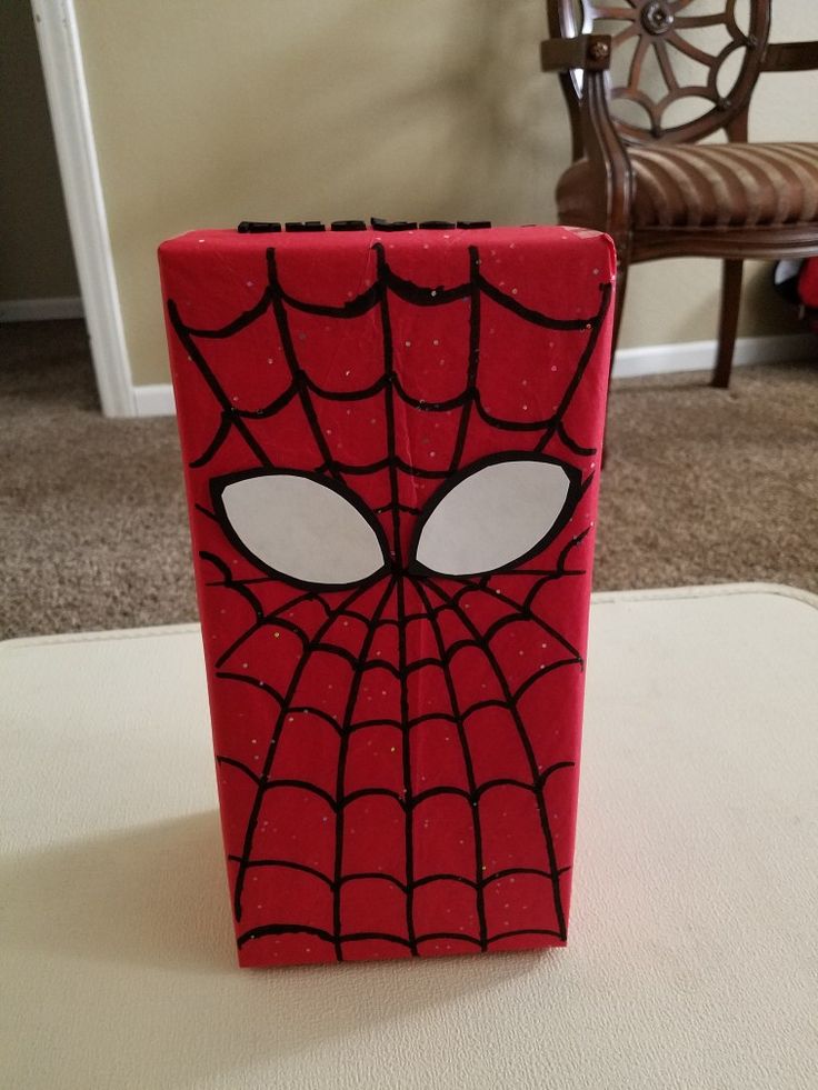 a red box with a spiderman face painted on it's side sitting on the floor