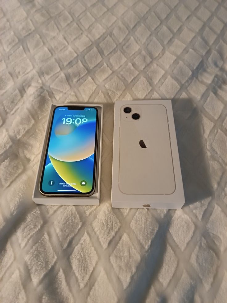 an iphone in its box sitting on a white bed with it's lid open