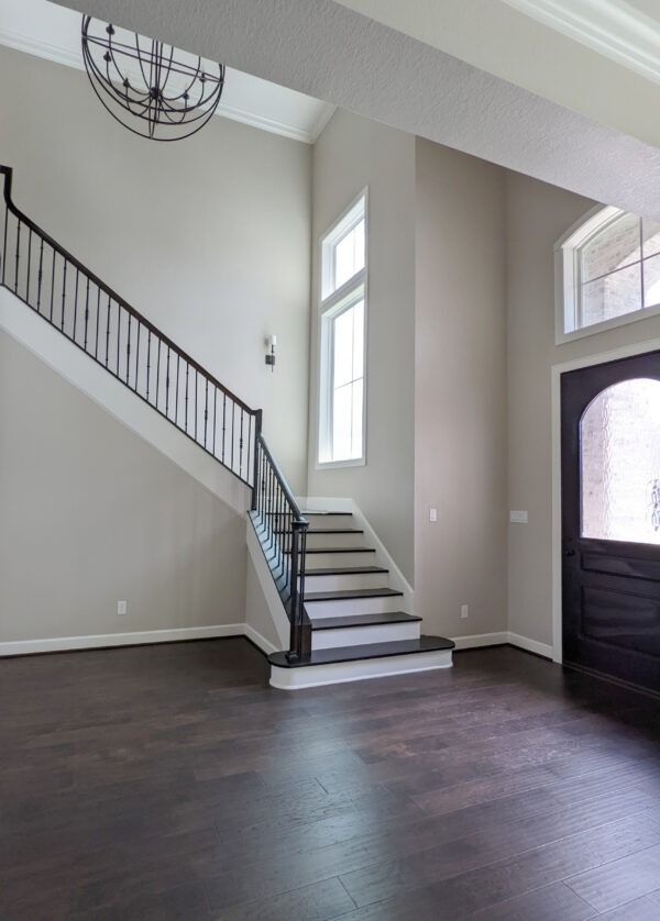 an empty living room with stairs leading up to the second floor and a black door