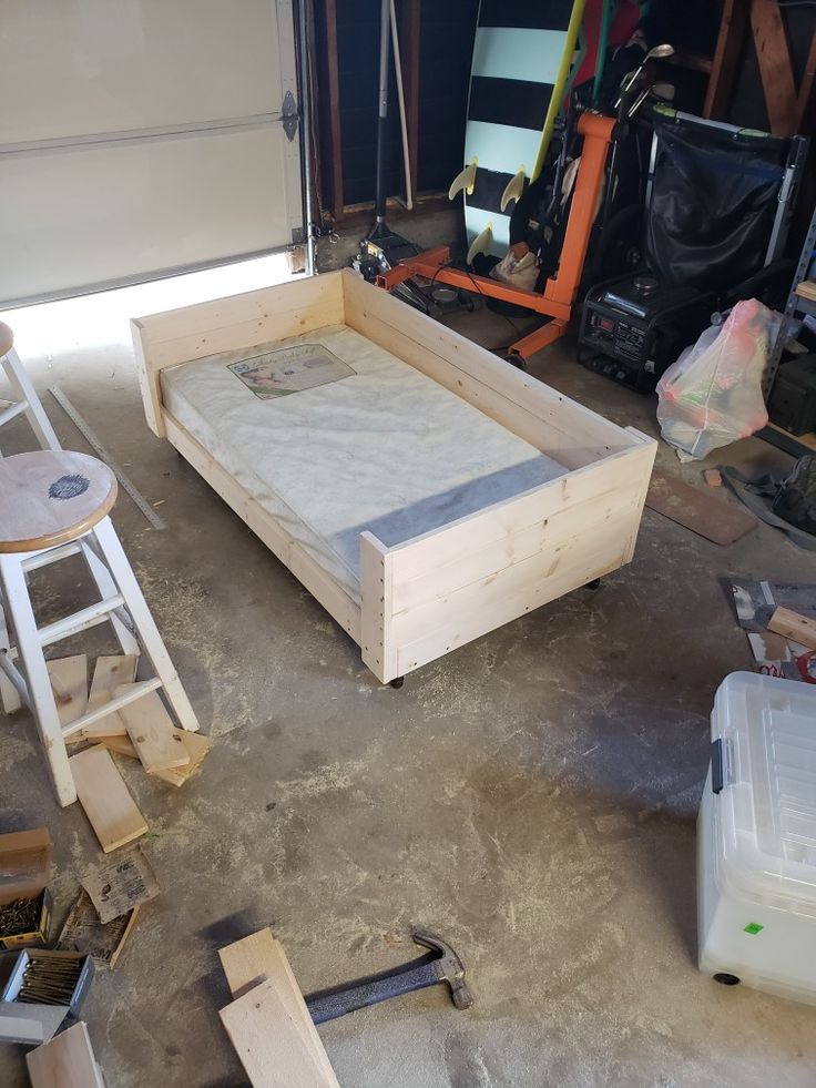 an unfinished bed frame in a garage with tools and other items around it on the floor