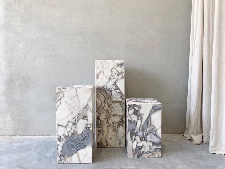 three marble blocks sitting next to each other in front of a white curtained window