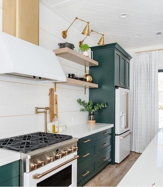 a kitchen with green cabinets and white counter tops, gold accents on the hoods