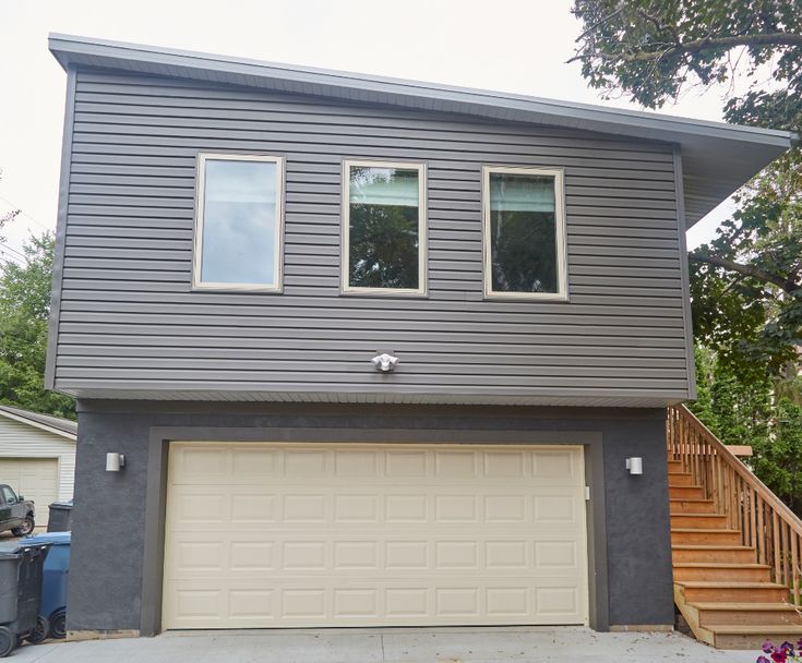 a two story house with garage and stairs leading up to it