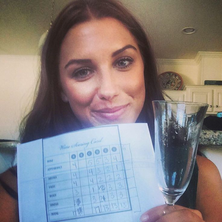 a woman holding up a wine glass and a paper with the word scrabble written on it