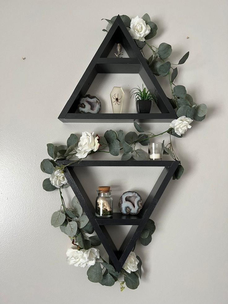 three shelves with plants and candles on them against a wall in the shape of a triangle