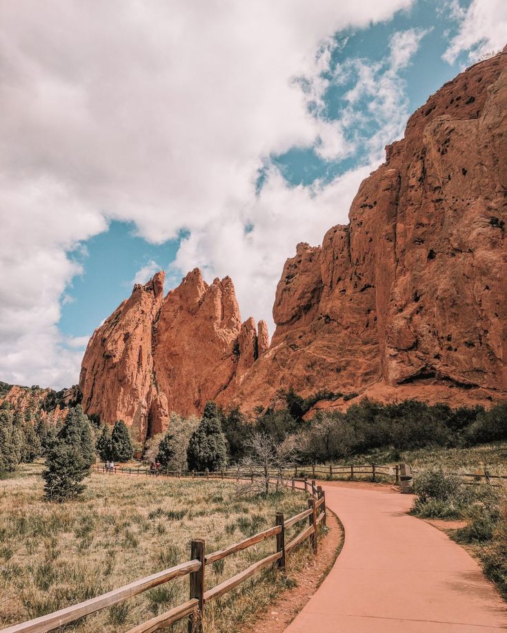 a dirt path in front of mountains and trees