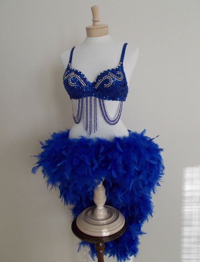 a mannequin with blue feathers and beads on it's chest is shown in front of a white wall