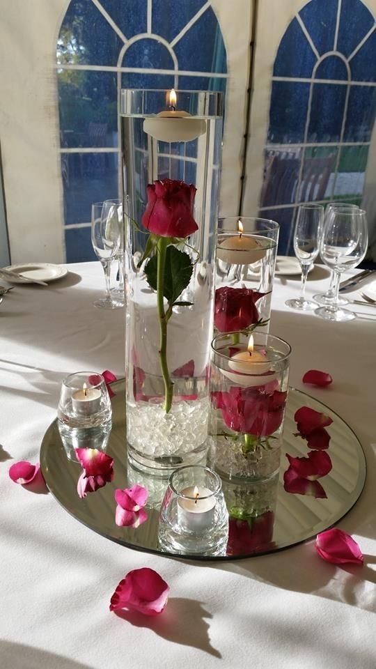 a centerpiece with flowers and candles on a table