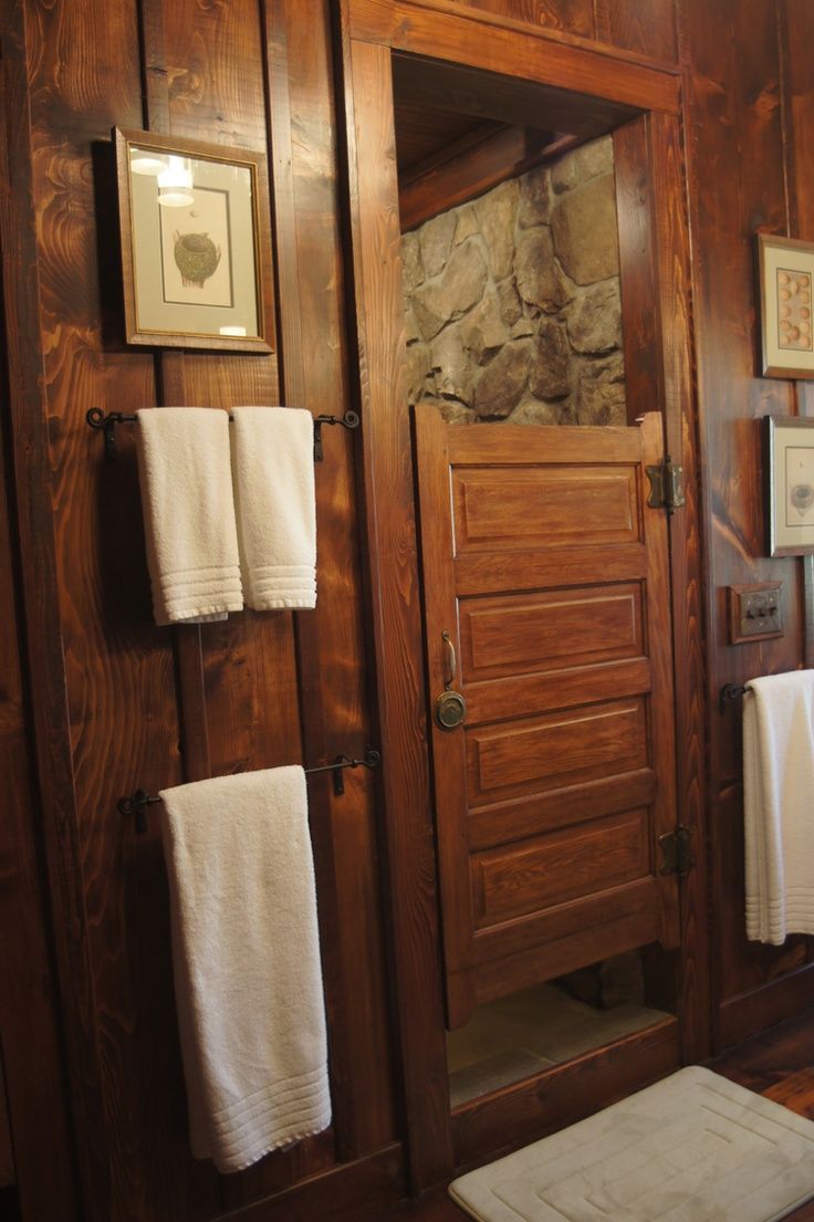 a bathroom with wood paneling and white towels hanging on the wall next to it