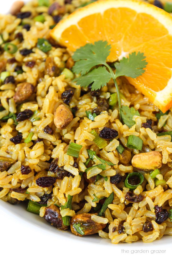 a white plate topped with rice and orange wedges next to a slice of lemon