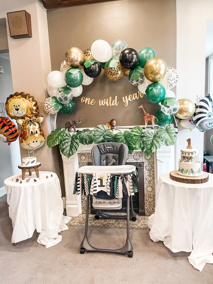 a baby's first birthday party decorated with balloons and streamers, jungle theme