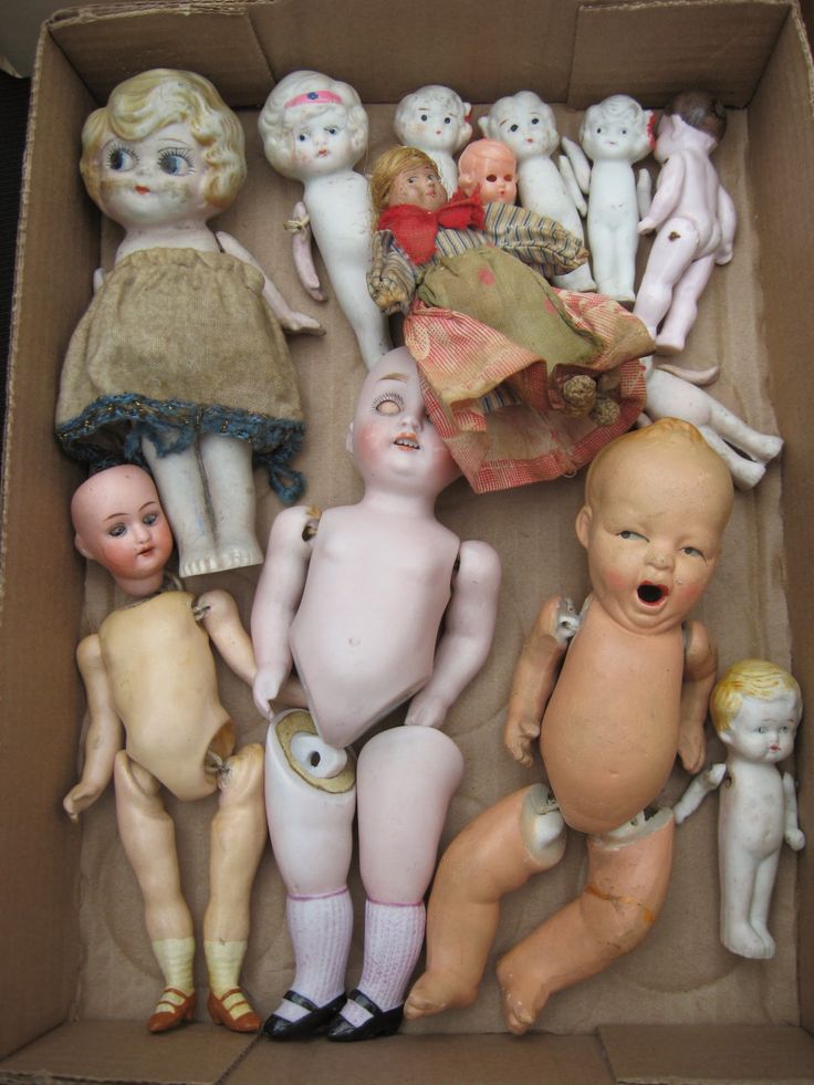 an open cardboard box filled with different types of doll heads and body parts in it