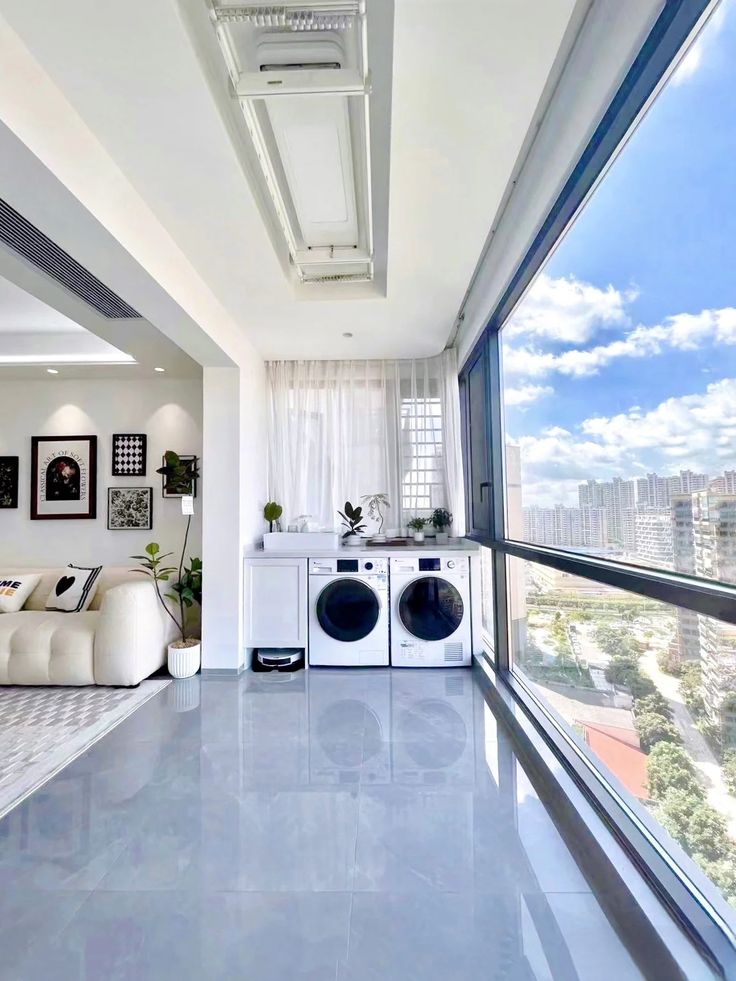 an empty room with a washer and dryer next to a large window overlooking the city