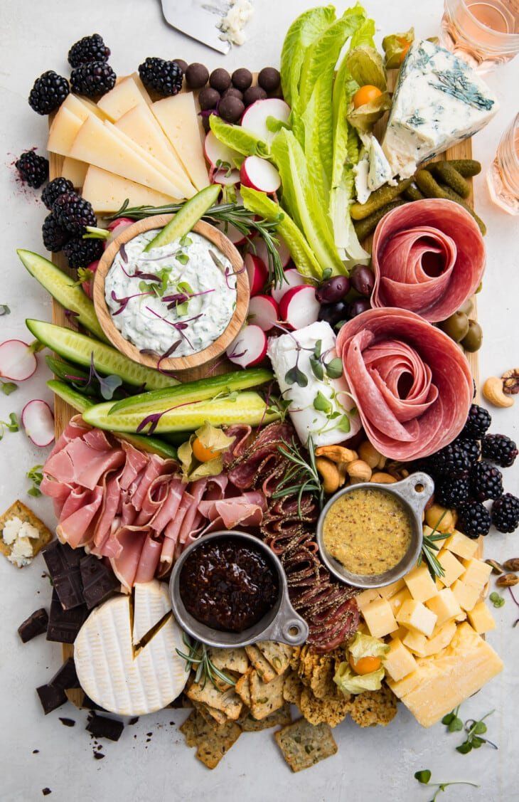 an assortment of cheeses, crackers and meats on a wooden platter