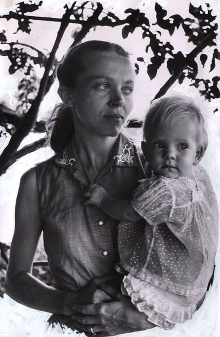 an old photo of a woman holding a small child in her arms and looking at the camera