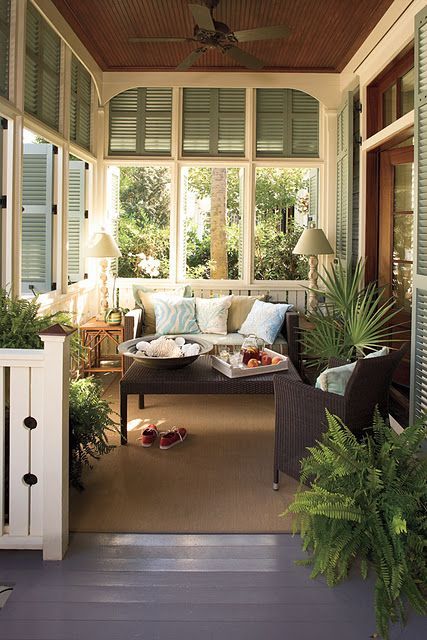 an enclosed porch with couches and potted plants