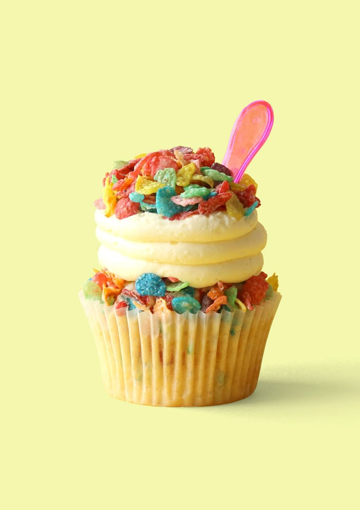 a cupcake with sprinkles and a pink spoon sticking out of it