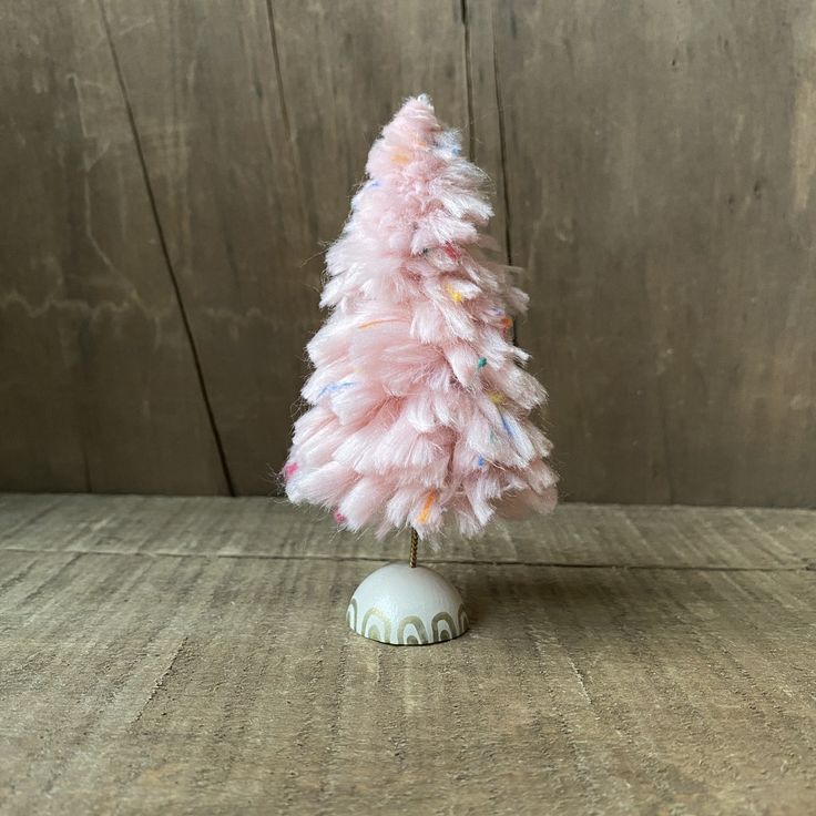 a small pink christmas tree sitting on top of a wooden table