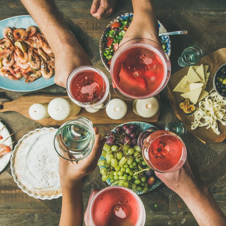 several people are toasting with drinks and food on the table