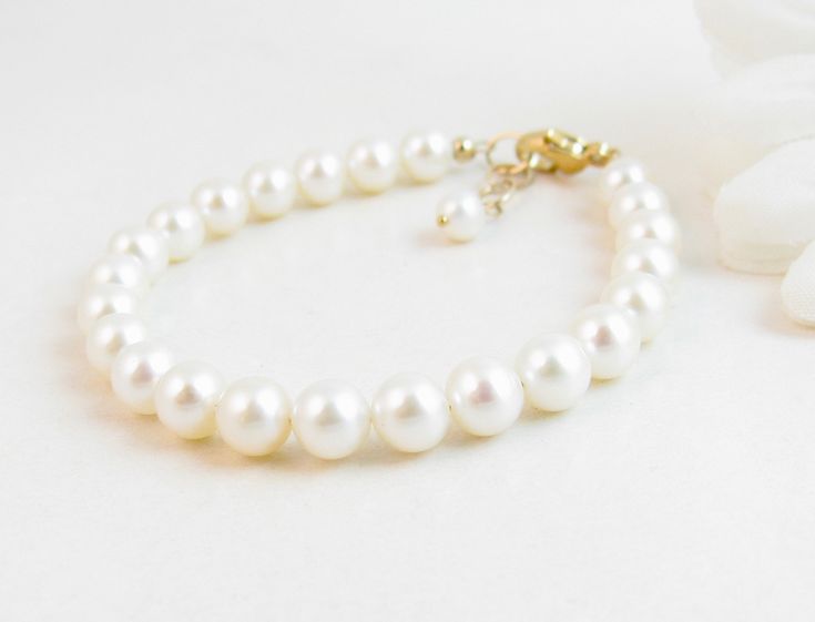 "A classic real freshwater pearl bracelet for newborn, infant, baby, child, little girl, tween or teen. This keepsake bracelet is created with Grade-A 5.5mm round freshwater pearls and a 14K gold-filled oval lobster clasp with a 1/2\" \"Grow with Me\" extender chain. Arrives packaged in my signature high-quality reusable canvas gift bag. Beautiful and ready for gift giving. S I Z I N G . G U I D E The bracelet should be 3/4\" larger than her snug wrist measurement. If you are unable to measure, Classic Adjustable Hypoallergenic Pearl Bracelet, Elegant Pearl Jewelry For Baptism, Elegant Adjustable Pearl Bracelet For Baptism, Elegant Pearl Rosary Bracelet For Baptism, Classic Adjustable Jewelry For First Communion, Elegant Pearl White Jewelry For Baptism, Elegant Pearl Bracelet For First Communion, Elegant Pearl Bracelet With Pearl Charm For First Communion, White Hypoallergenic Pearl Bracelet For First Communion