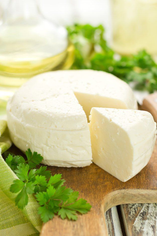 a piece of cheese on a cutting board with parsley