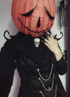 a woman wearing a pumpkin mask and black dress