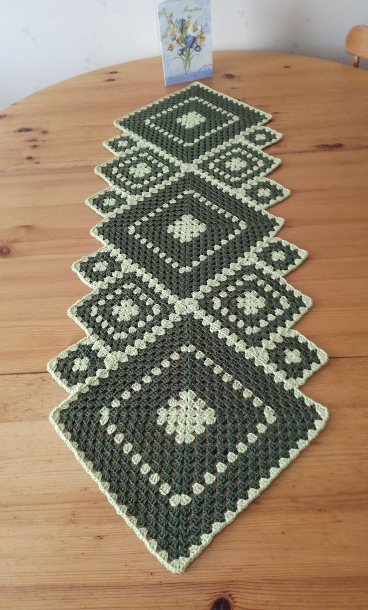 a wooden table with a green and white crocheted rug on top of it