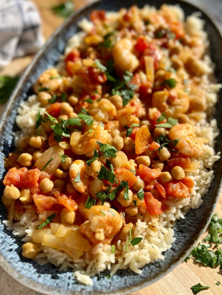 a blue plate filled with rice and vegetables on top of a wooden table next to a napkin