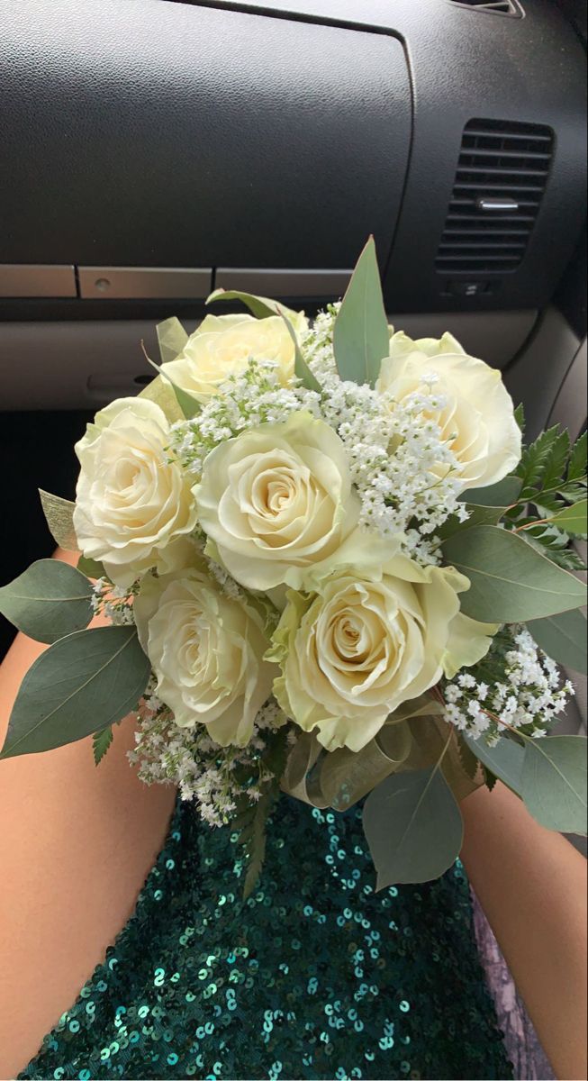 a bouquet of white roses and baby's breath sits in the passenger seat of a car