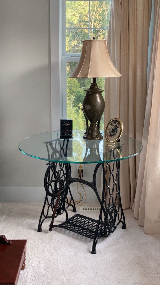 a table with a lamp on top of it in front of a window and curtains