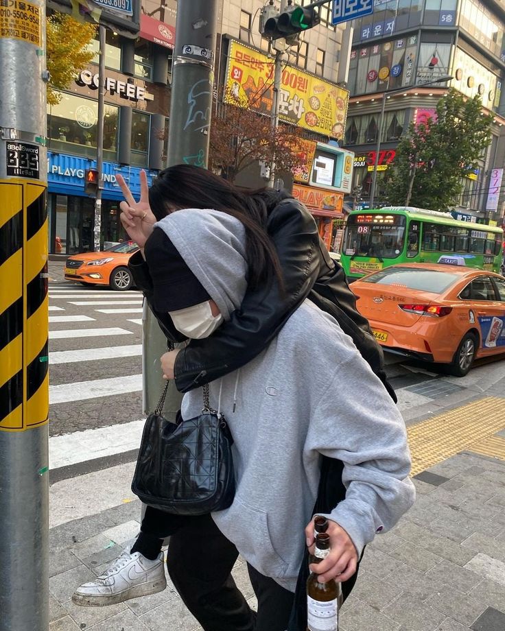 a woman standing on the side of a street holding her hand up to her face